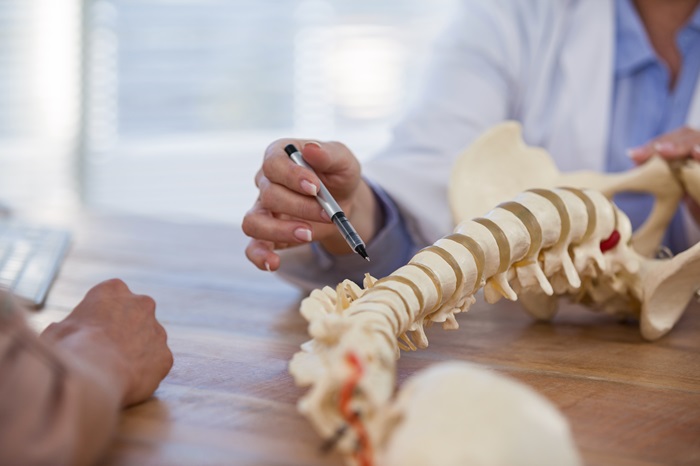 Doctor demonstrating spine condition to a patient with a model