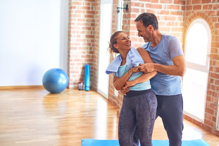 Middle age sporty couple smiling happy. Standing with smile on face hugging at gym