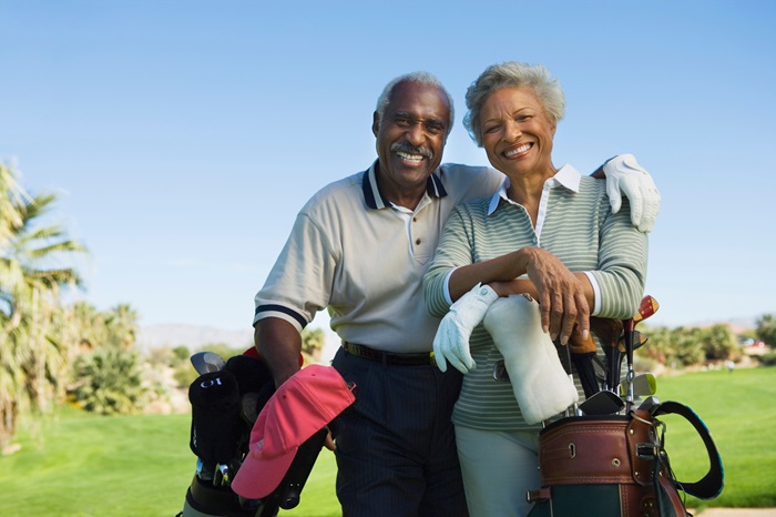 Happy married senior couple golfing.