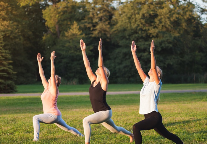 Yoga at park, group of mixed age women doing pose while sunset