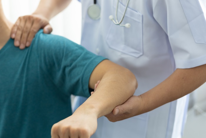Concept of physical therapy and rehabilitation. A man with shoulder pain goes to the doctor, The doctor diagnoses the patient's arm pain and shoulder pain.