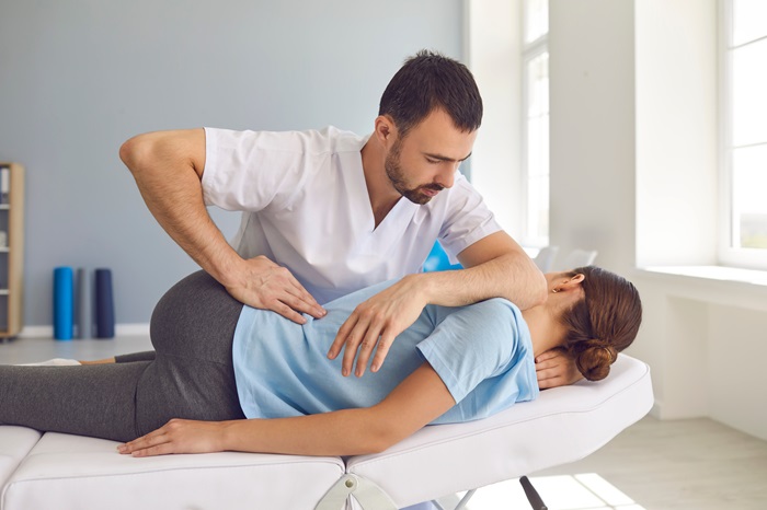 Chiropractor adjusting patient on table