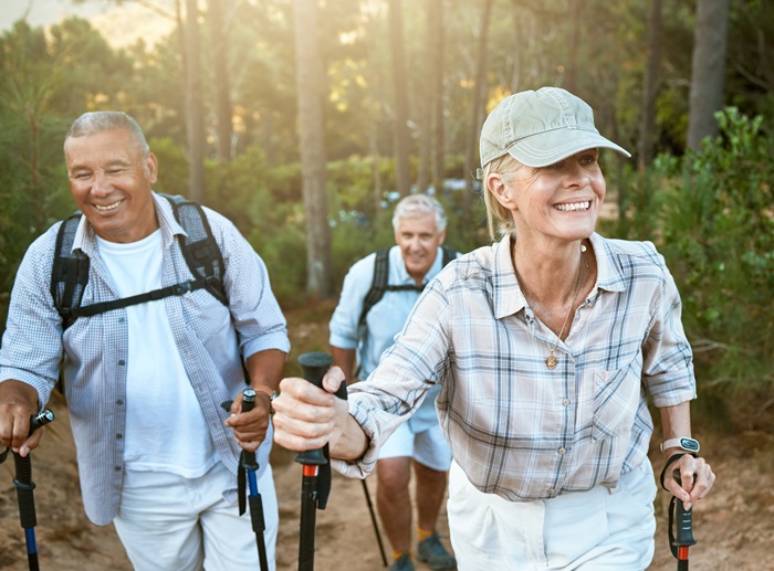 Hiking retired, elderly and senior friends or tourists in forest or mountains for fitness, health and wellness at old age. Diverse group of active mature pensioners outdoors on weekend hike in nature.