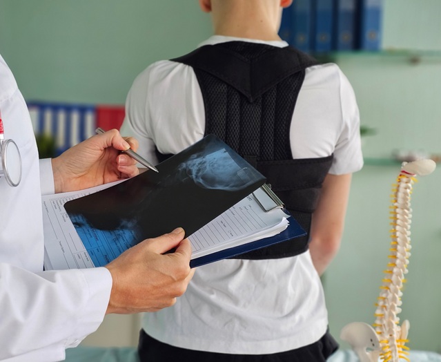 Orthopedic doctor fitting back brace to patient