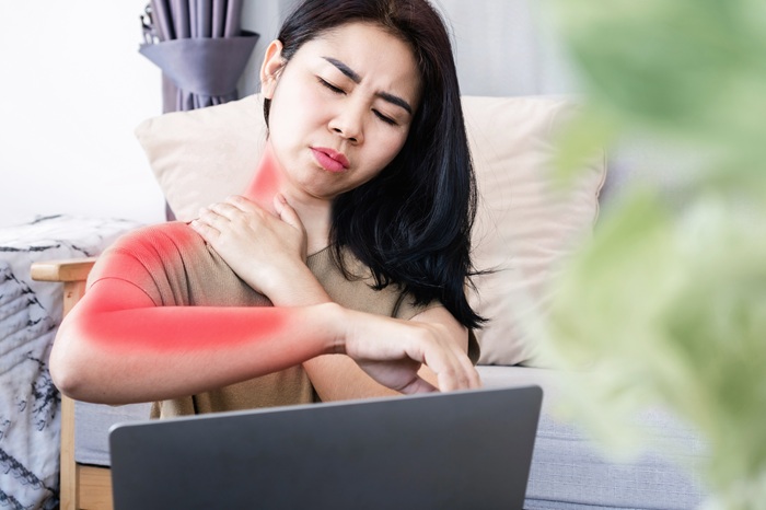 Woman with radiating neck pain working on a laptop