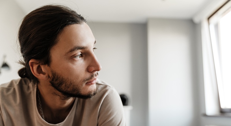 Depressed man sitting on the corner of his bed